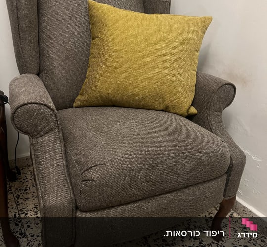 כורסת אוזניים מרופדת בבד אפור עם כרית נוי צהובה